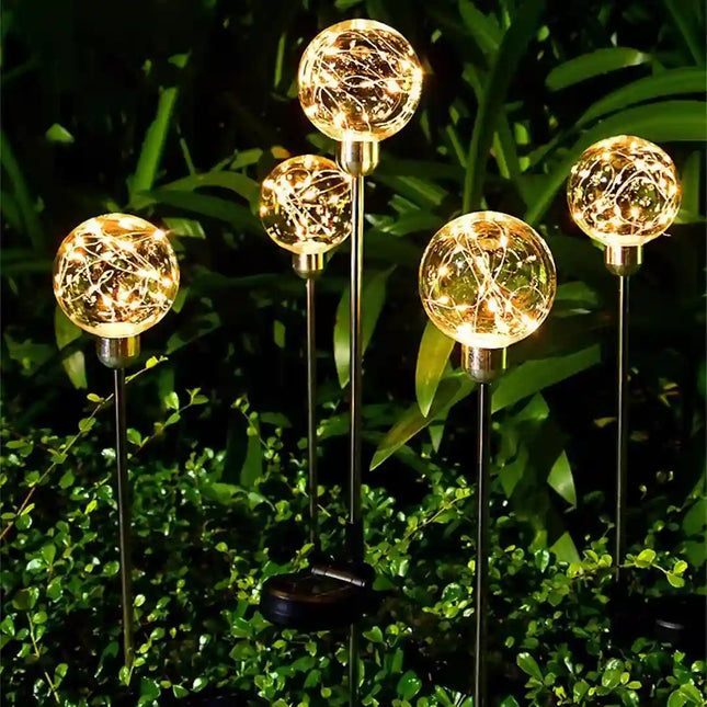 Transparent ball solar light illuminating a garden pathway with warm white decorative lighting.